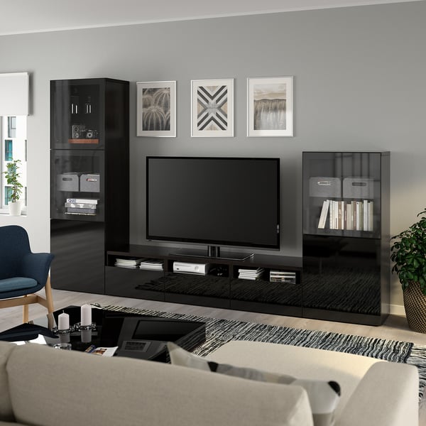 Modern living room with large tv on BESTÅ stand, sound system, books, and decor. Gray walls, sofa, coffee table, chair, and plant.