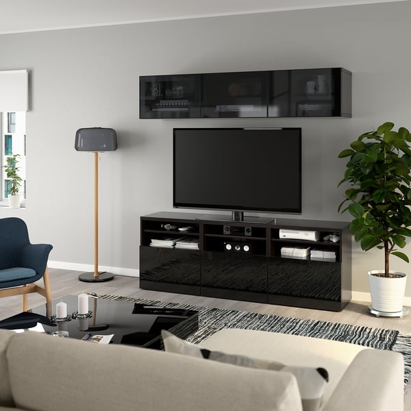 Modern living room: large flat-screen tv on glossy black BESTÅ stand; wall-mounted storage, potted plant, cozy sofa, and lamp.