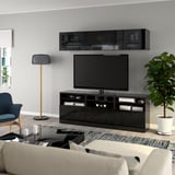 Modern living room: large flat-screen tv on glossy black BESTÅ stand; wall-mounted storage, potted plant, cozy sofa, and lamp.