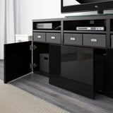 Black tv stand with open doors revealing organized storage. It supports a flat-screen tv on top, featuring adjustable shelves and cable management.