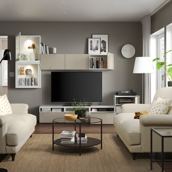 Modern living room with light-colored furniture, including sofas, a coffee table, and a tv stand with adjustable shelves and cable management.