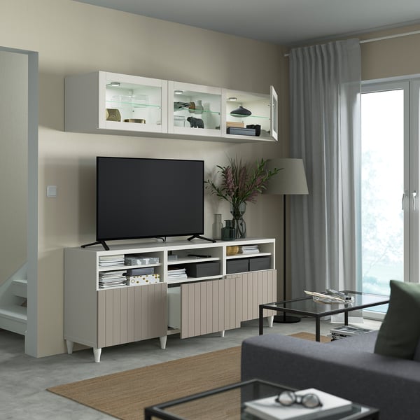 Modern living room with light-colored furniture. A tv is on a storage unit with cabinets, shelves, and cable management.