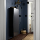 Modern entryway with dark grey BESTÅ cabinet, black handles, and wicker basket, mounted on a dark blue wall.