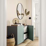 Modern entryway with light blue BESTÅ storage unit, white walls, round mirror, and dried plants.