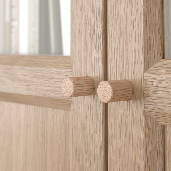 Wooden cabinet with two round knobs; smooth, light wood finish and clean design.