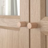 Wooden cabinet with two round knobs; smooth, light wood finish and clean design.