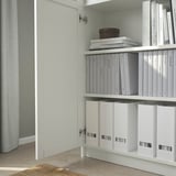 A BILLY bookcase with adjustable shelves and a white door, displaying neatly organized files and books.