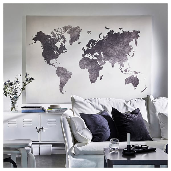Large wall map art, modern living room with white couch, black pillows, side table with wine glass, candle, and remote.