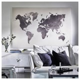 Large wall map art, modern living room with white couch, black pillows, side table with wine glass, candle, and remote.