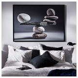 Bedroom with BJÖRKSTA black & white art, white bed with black & gray pillows, nightstand, lamp, phone.