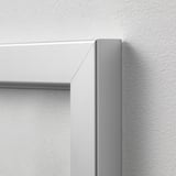 Large metal picture frame corner; modern, sleek design; mounted on white wall.