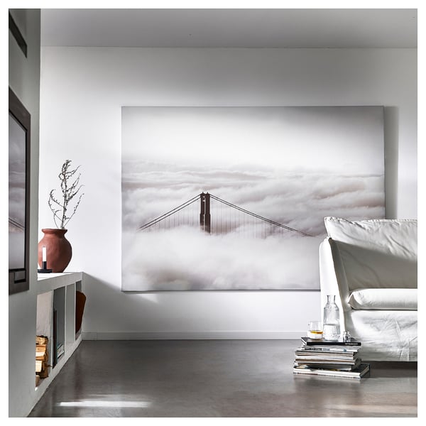 Living room with golden gate bridge print, books, bottles, and vase with branches.