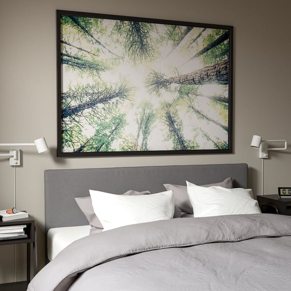 BJÖRKSTA forest scene wall art above bed with lights.