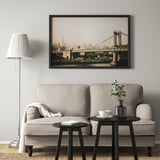 Minimalist living room with large bridge art, BJÖRKSTA sofa, two black tables, lamp, and a central framed picture.