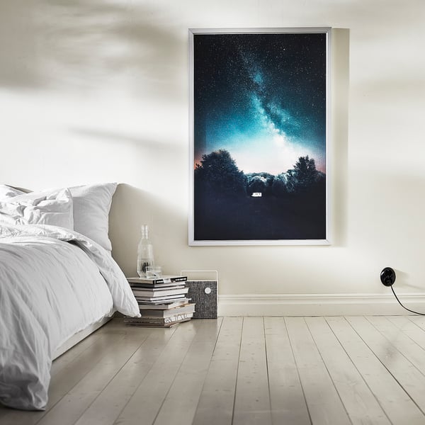 Bedside starscape art, books, white bed.