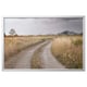 A BJÖRKSTA framed picture with a dirt road through a grassy field and mountains in the distance. It is encased in a silver aluminum frame.