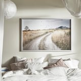 Bedroom with BJÖRKSTA landscape print above bed, white pillows.