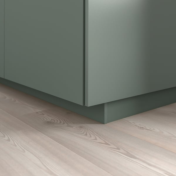 Green kitchen cabinet base with matching plinth covering floor gap.