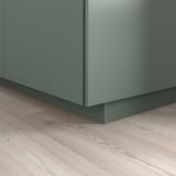 Green kitchen cabinet base with matching plinth covering floor gap.