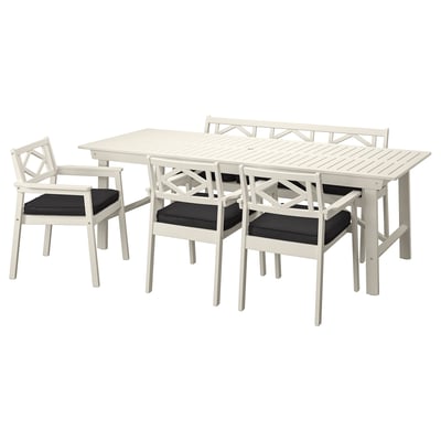 White acacia outdoor dining set with table and 6 cushioned chairs.