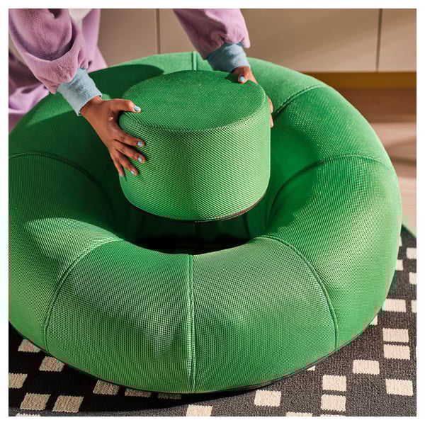 Person adjusting an inflatable green BRÄNNBOLL lounge chair, demonstrating its ability to be easily moved and positioned.