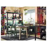 Modern kitchen with BROR storage shelves, green chairs, wood table, hanging plants, colorful curtains, and various kitchen items.