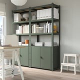 BROR green storage: shelves with books, boxes, & decor. White desk, chair, & stool at sides.