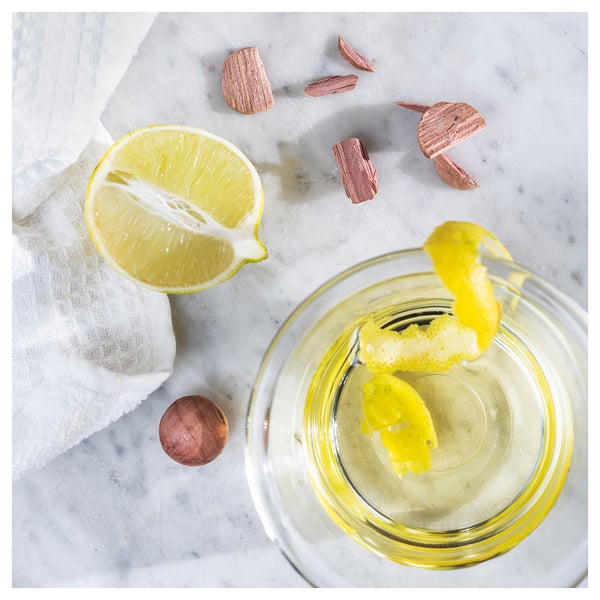Sliced lemon, jar with lemon zest, wood pieces on marble.