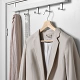 Wooden hanger with a beige jacket and scarf on hooks.