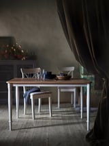 A DANDERYD dining table, white with oak veneer top, rectangular, surrounded by four matching chairs, set for dining with tableware.