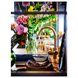 Kitchen scene with DELSJÖN gold-colored faucet and sink. Colorful flowers in vase, tools, and jars on counter. Modern decor.