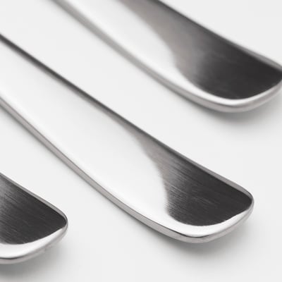 Six polished stainless steel spoons with evenly rounded bowls, lined neatly in a row; timeless and durable design.