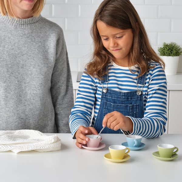 Child pours tea using toy set, promoting imaginative play and fine motor skills with colorful cups and saucers.