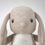 Soft stuffed bunny toy with long ears, embroidered eyes and nose. Neutral beige color.