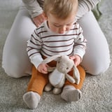 Baby sits, holding stuffed bunny toy, both comfortable and safe for play.