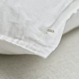 Close-up of white linen cushion cover with hidden zipper, showcasing soft, textured fabric.