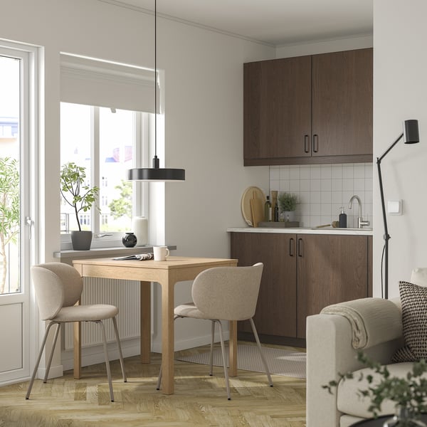 Modern living room with extendable dining table, chairs, wood cabinet, and sleek decor. Bright lighting highlights wooden floor and minimalist design.