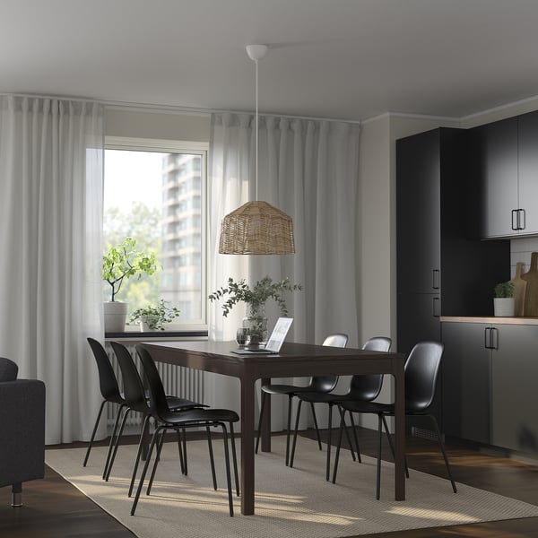 Modern dining set with extendable table, black chairs, and wicker light. Large window with grey curtains lets in natural light.
