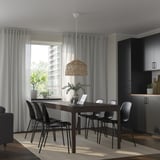 Modern dining set with extendable table, black chairs, and wicker light. Large window with grey curtains lets in natural light.