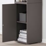Black EKET cabinet with one door open, revealing shelves holding books and storage boxes.