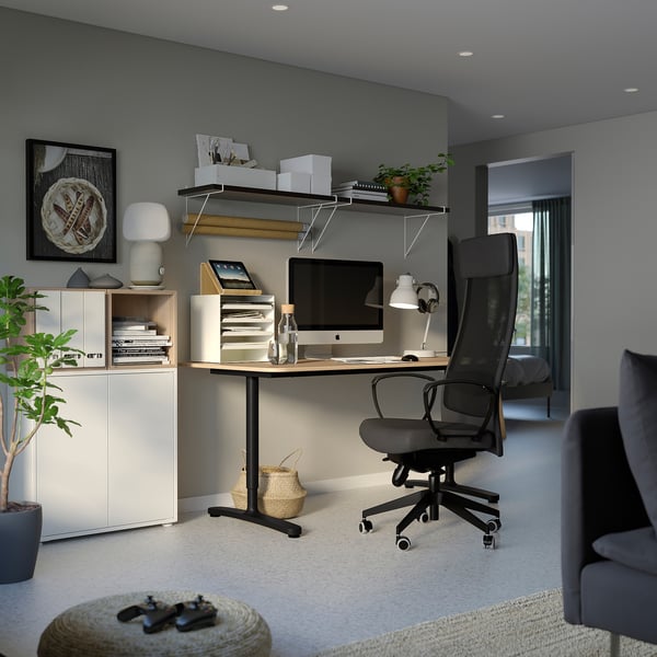 Modern home office an EKET white storage unit, wooden desk, black office chair, and various decorative items.
