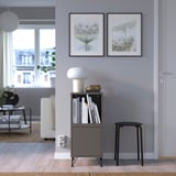 Modern living room with black EKET storage, books, decor, and floral art prints.
