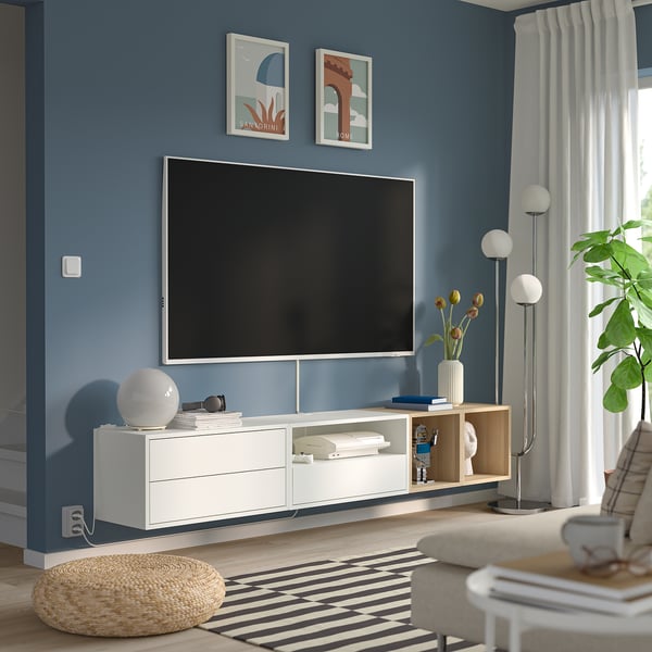 Modern blue living room with EKET tv unit, posters, lamp, plant, and rug.