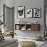 Wall-mounted shelves with art, books, light furniture, grey rug, sofa.