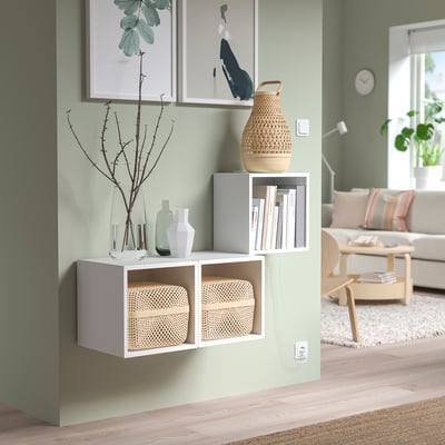 Minimalist living room with EKET storage, wicker boxes, vases, books, plant, art, and sofa.
