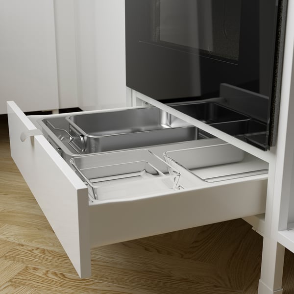 Open kitchen drawer revealing multiple stainless steel compartments, designed for storing baking trays and pans.
