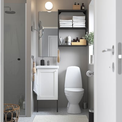 Modern white bathroom with sink cabinet, high toilet, towels, mirror.