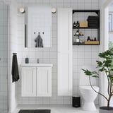 Modern white bathroom with ENHET vanity, mirror, storage, and greenery.