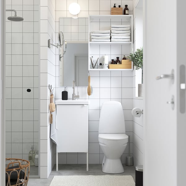 Modern white bathroom with ENHET vanity, toilet, open shelves, mirror, and shower.