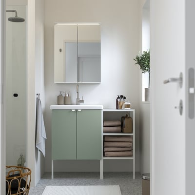 Modern bathroom with light green ENHET vanity, mirror cabinet, open shelves, white basin, and gray towels.